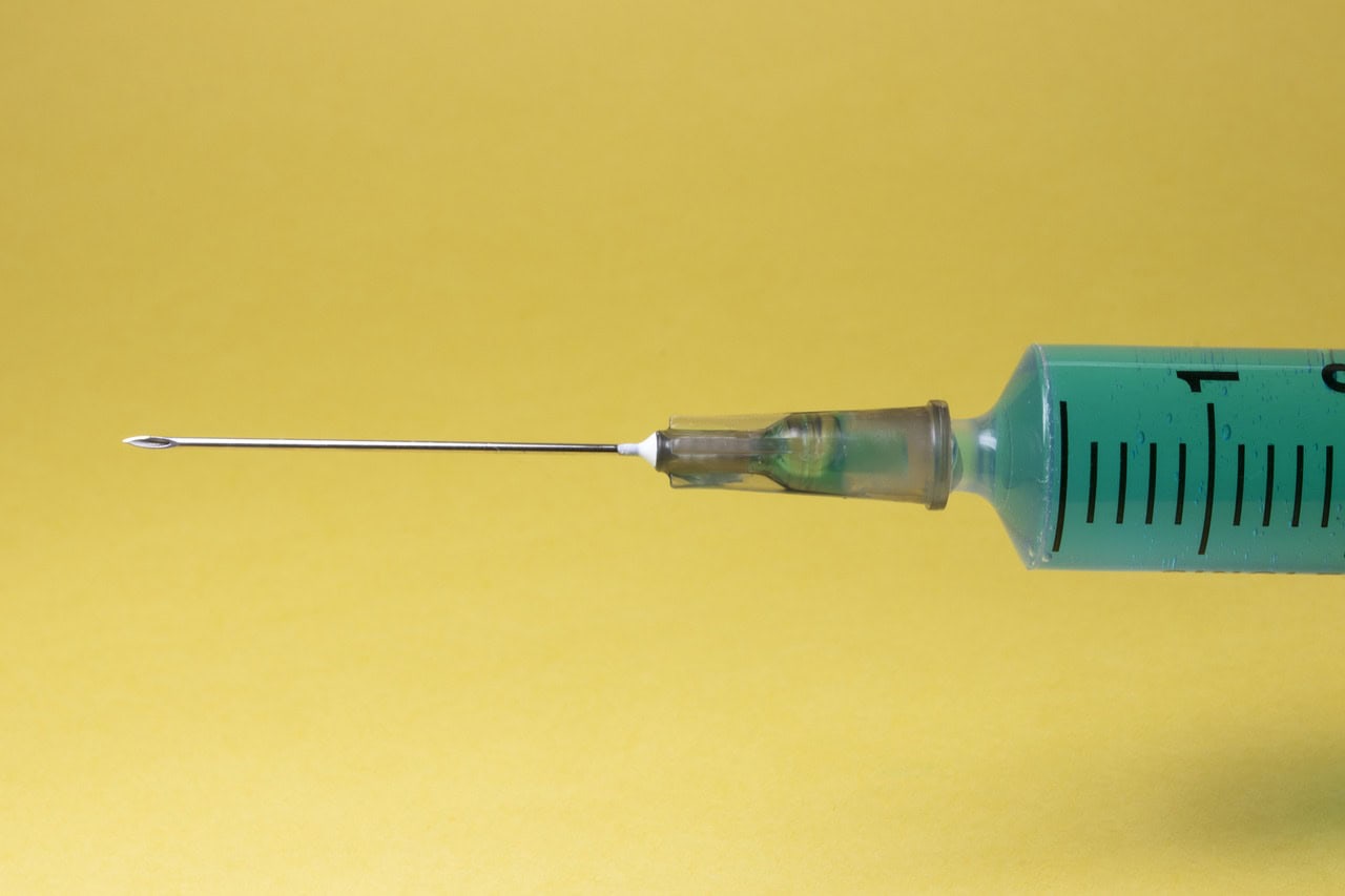 Syringe on yellow background How long does Ozempic stay in your system?