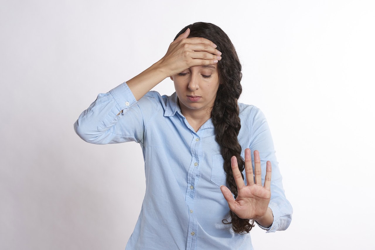 Woman in blue shirt with hand on head ozempic headache