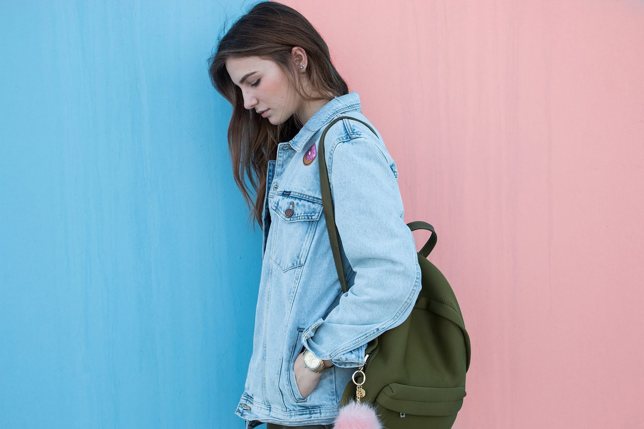 Woman wearing a denim jacket with a pink and blue background